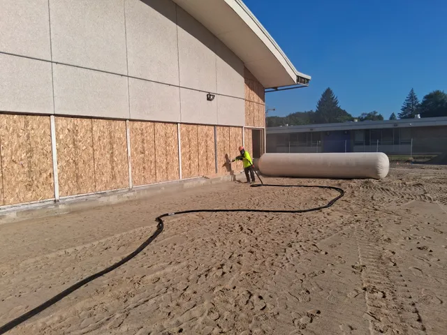 Blasting exterior wall panels on a public school gymnasium during renovation
