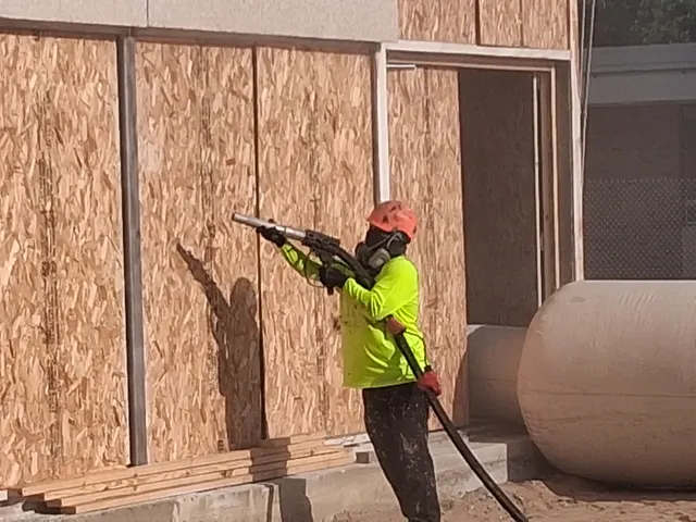 Close-up of blasting nozzle on public school gymnasium exterior wall