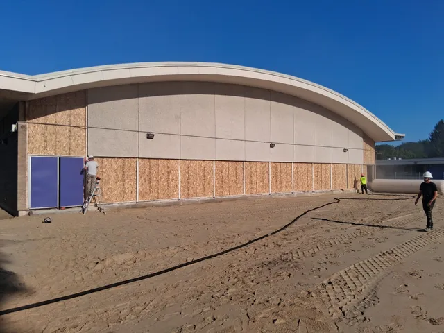 Blasting crew and equipment staged outside a public school gymnasium during renovation