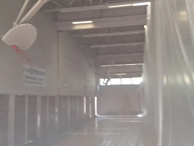 Interior of public school gymnasium with dust containment sheeting during blasting