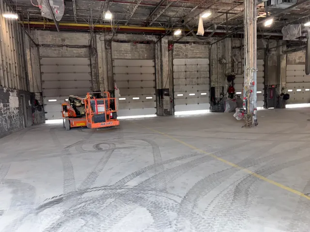 Semi-truck maintenance bay with exposed blasted ceiling and support columns