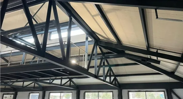 Coated structural steel trusses and mezzanine with cable railing under skylights